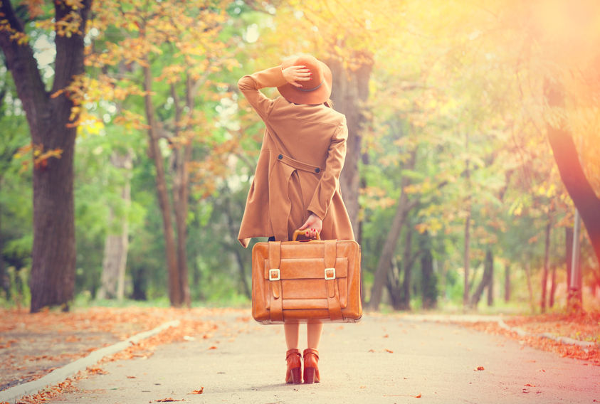 Frau mit Koffer in einem Park im Herbst